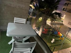 a table and two chairs on a balcony with a table and a playground at appartement de lux vue piscine 5 min plage bouznika in Bouznika
