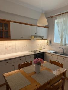 a kitchen with a wooden table with a vase of flowers on it at Rosie Apartment in Preveza