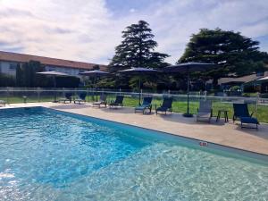 a swimming pool with chairs and umbrellas at Ariane Hôtel Fos sur Mer in Fos-sur-Mer