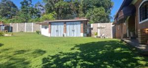 a yard with a building with a white garage at Chácara Maira e Araken in Ibiúna