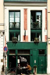 un uomo seduto davanti a un edificio verde di Chez Georges - Auberge Contemporaine a Lille