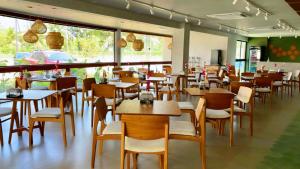 a restaurant with wooden tables and chairs and windows at Malia Beach in Ipojuca