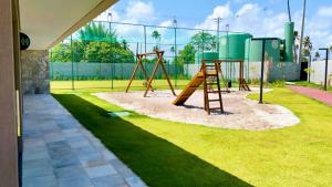 a playground with a wooden swing set in a yard at Malia Beach in Ipojuca
