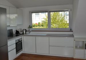 een keuken met witte kasten en een raam bij Ferienwohnung Am Bergle in Überlingen