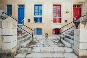 a building with red and blue doors and stairs at Senglea town house in Senglea