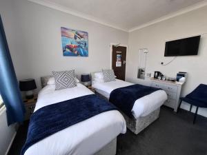 a hotel room with two beds and a television at Westbrook Lodge Guest House in Margate