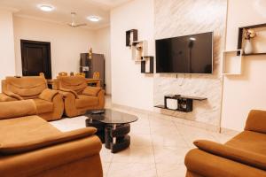 a living room with couches and a flat screen tv at Executive 2 Bed RealShala Properties-Adjiringanor in Ashalebotwe