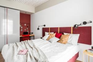 a bedroom with a large white bed with red accents at Neptun Park Premium by NorthSide Apartments in Gdańsk
