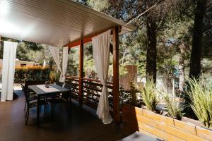 a table and chairs on a porch with trees at Mobile Home Amélie - Oaza Mira Camping in Drage