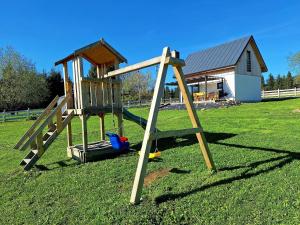 a playground with a wooden swing set in a field at SierPlejs Hill - domki przy szlaku w Górach Sowich in Sierpnica