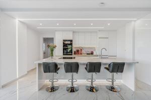 a kitchen with a island with four black bar stools at Sea View Residence Panorama Villa in Saronida