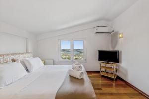 a white bedroom with a large bed and a television at Sea View Residence Panorama Villa in Saronida +43 photos