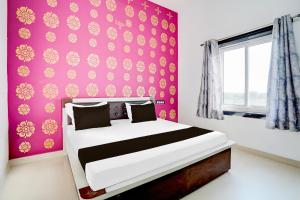 a bedroom with a bed with a pink wall at Hotel O Udayraj and Restuarant in Kuchāman