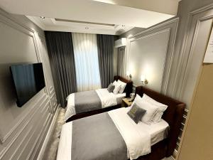 a hotel room with two beds and a flat screen tv at Qadim Hotel in Samarkand