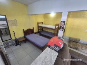 a small room with two beds and a table at Kitão Completo ao lado da Balsa Bertioga in Bertioga