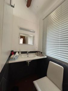 a bathroom with a sink and a chair and a mirror at La Petite Maison in La Celle-sous-Gouzon