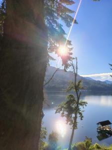 a view of a lake with the sun shining at Dos Bahias Lake Resort in Villa La Angostura