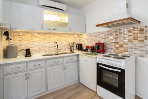 a kitchen with white cabinets and a stove top oven at MANOS Small House Kouremenos in Palekastron +58 photos