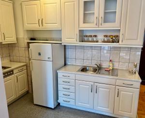 een witte keuken met een wastafel en een koelkast bij RingRoad Apartment in Ohrid