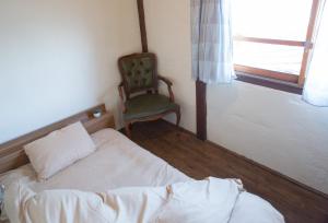 a bedroom with a bed and a chair and a window at Dot Hostel Nagano in Nagano