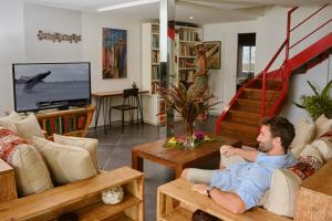 a man sitting on a couch watching tv in a living room at Villa Vaihere in Orufara