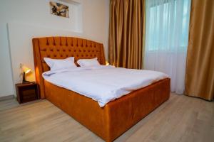 a bedroom with a large wooden bed with white sheets at Sand Vibe RIN Grand Hotel in Bucharest