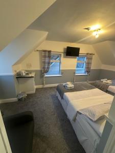a room with two beds and a tv and two windows at Kinsale B&B in Scilly