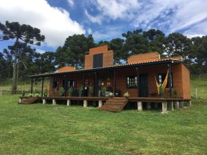a large wooden house with a deck in a field at Rancho do Tigre in São Joaquim