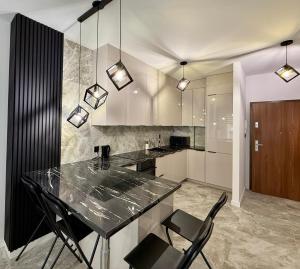 a kitchen with a black counter and black chairs at Drahan Apartment 14 in Radom