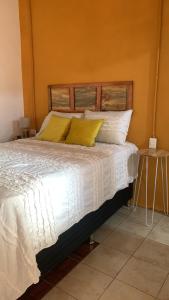 Un dormitorio con una cama con sábanas blancas y almohadas amarillas. en El Chirris B&B, en San Juan La Laguna