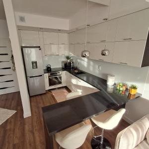 a kitchen with white cabinets and a black counter top at Apartament Sikorskiego, klimatyzacja, parking monitoring in Suwałki
