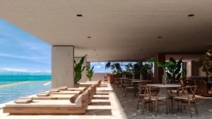 a restaurant with tables and chairs and the ocean at Sais Beach Living Hotel in Maceió