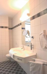 a white bathroom with a sink and a mirror at Stadthotel Crailsheim in Crailsheim