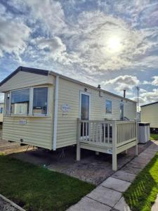リルにあるLovely 6 Berth Caravan At Sun Valley In North Wales Ref 81023Aのポーチと曇り空のあるトレーラーハウス