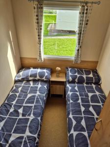 リルにあるLovely 6 Berth Caravan At Sun Valley In North Wales Ref 81023Aの窓のある小さな部屋にベッドが2つある +8枚の写真
