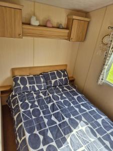 リルにあるLovely 6 Berth Caravan At Sun Valley In North Wales Ref 81023Aのベッドルーム1室(ベッド1台に青と白の掛け布団付)