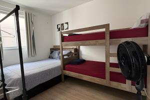 a bedroom with two bunk beds and a fan at Apto prático | 2 Qtos + Lazer + Garagem in Perequê +35 photos