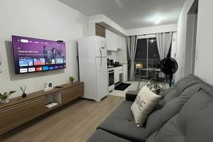 a living room with a gray couch and a kitchen at Apto prático | 2 Qtos + Lazer + Garagem in Perequê