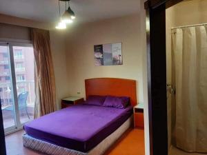 エル・アラメインにあるجولف بورتو ماريناの紫色のベッドと窓のある寝室