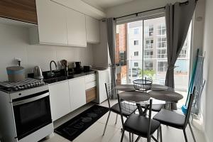 a kitchen with white cabinets and a table with chairs at Apto prático | 2 Qtos + Lazer + Garagem in Perequê
