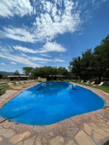 a large blue pool with chairs and a blue sky at La Posada De Juan in Cabra Corral