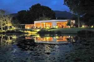 una casa con un estanque delante de ella por la noche en Lily Pond Country Lodge, en The Crags