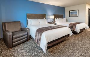 a hotel room with two beds and a chair at My Place Hotel-Jacksonville-Camp Lejeune, NC in Jacksonville