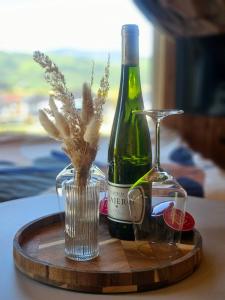 a bottle of wine on a wooden tray with a glass at AleWidok - domek z sauną i widokiem na Góry Sowie in Ostroszowice