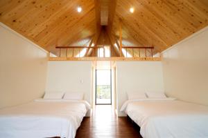 2 Betten in einem Zimmer mit Holzdecken in der Unterkunft Artisan Hostel in Toucheng