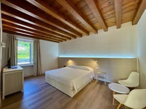 a bedroom with a bed and two chairs and a television at Corte Impero Hotel & Restaurant in Affi