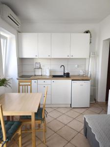 a kitchen with white cabinets and a wooden table at City apartment Rina in Crikvenica