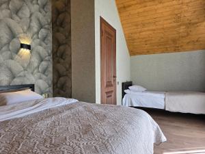 una camera da letto con due letti e soffitto in legno di Kazbegi Folk Cottages a Kazbegi