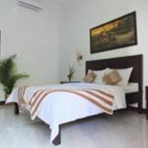 1 dormitorio con 1 cama con sábanas y almohadas blancas en Ricel Homestay, en Gili Trawangan