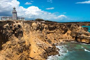 a lighthouse on a cliff next to the ocean at I Love Combate Rooms & Suites in Boqueron